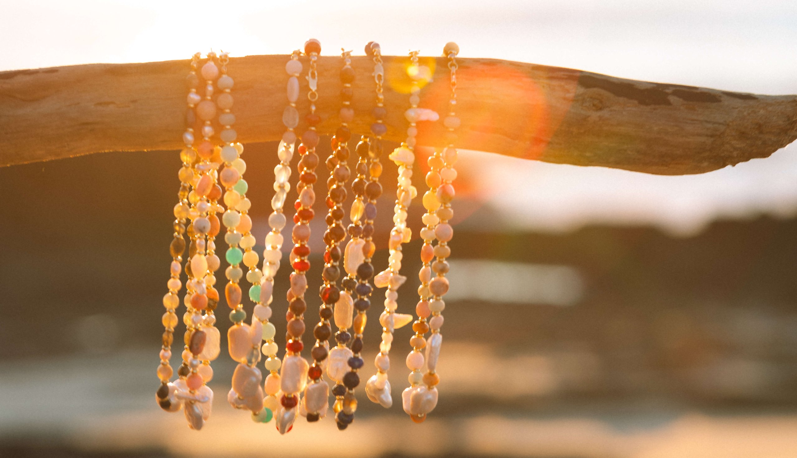 Daisy Kay necklaces resting on driftwood